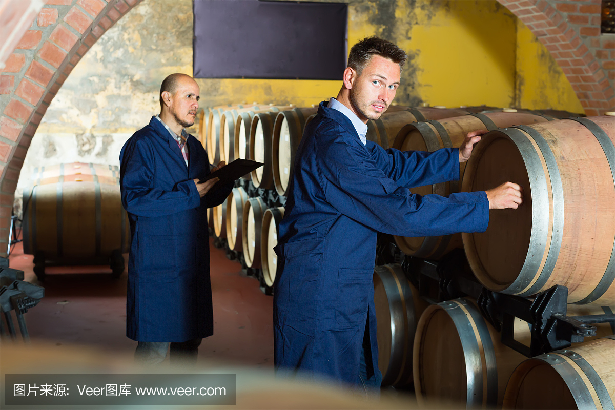 兩個(gè)穿著制服的男人微笑著在酒窖里做筆記