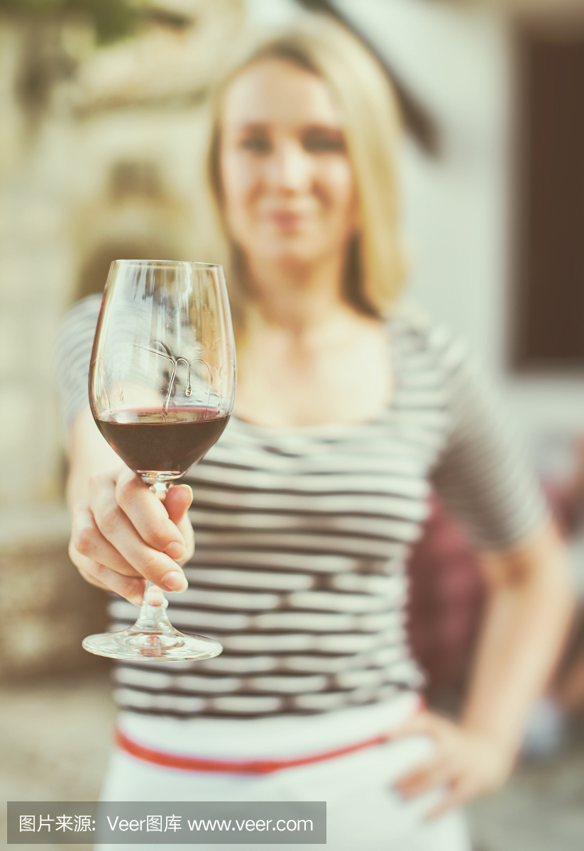 一個女人在室外遞上一杯紅酒。復古的效果。